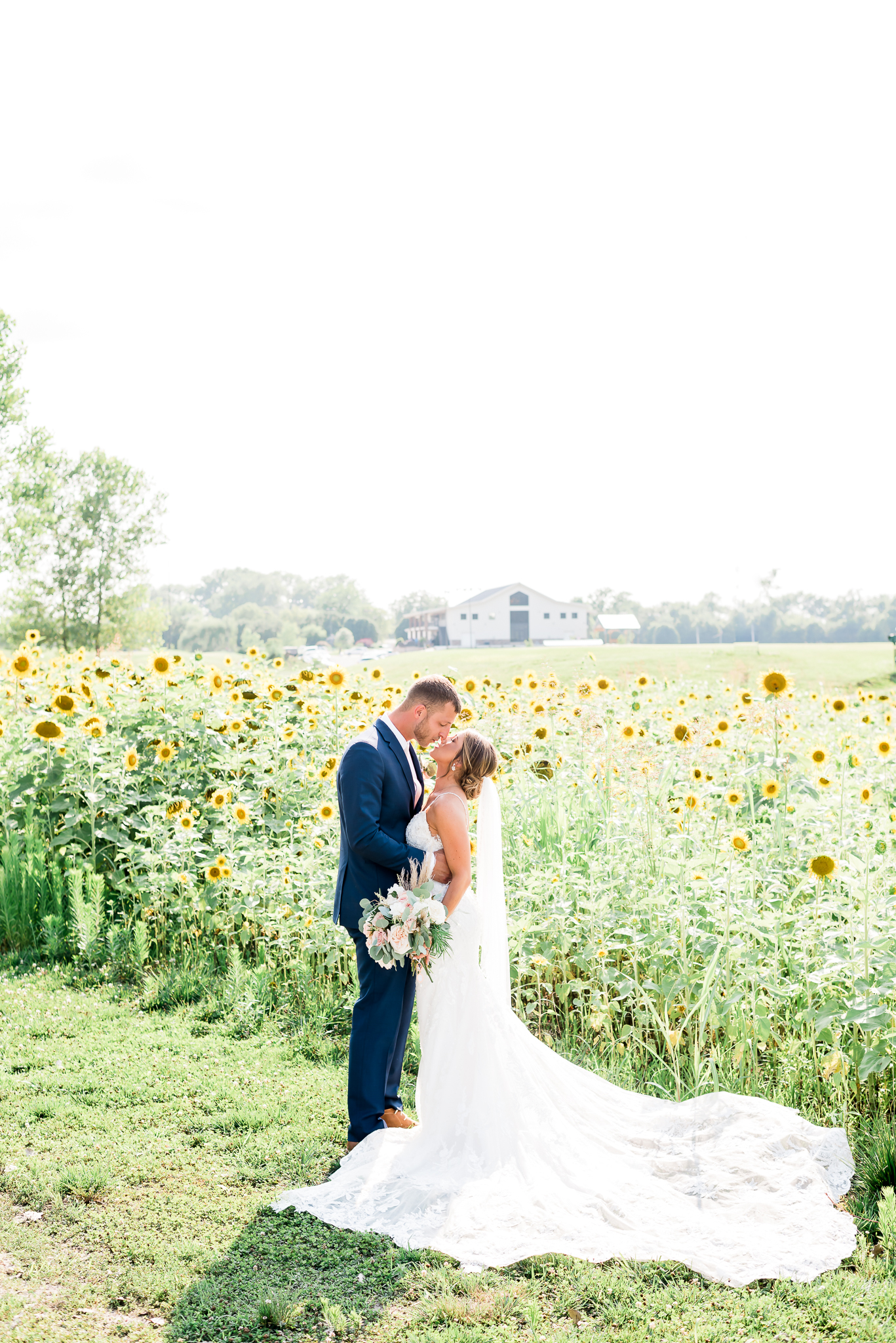 bride and groom kissing in field of sunflowers