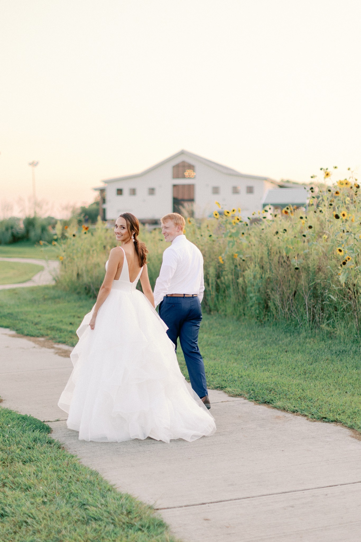 bride and groom walking by sunflowers