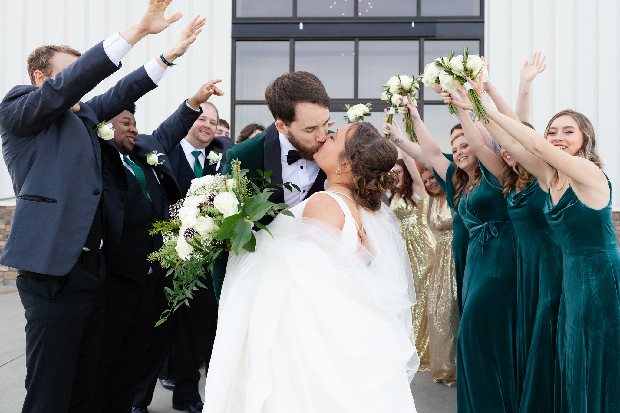 couple kissing while wedding party cheers