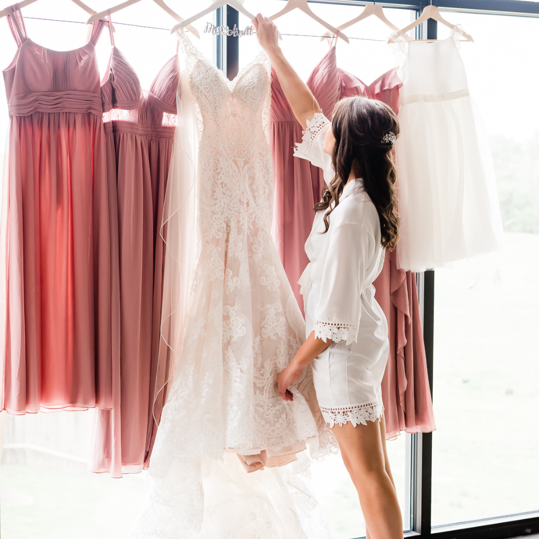 bride holding her gown with bridesmaids'' gowns in the background