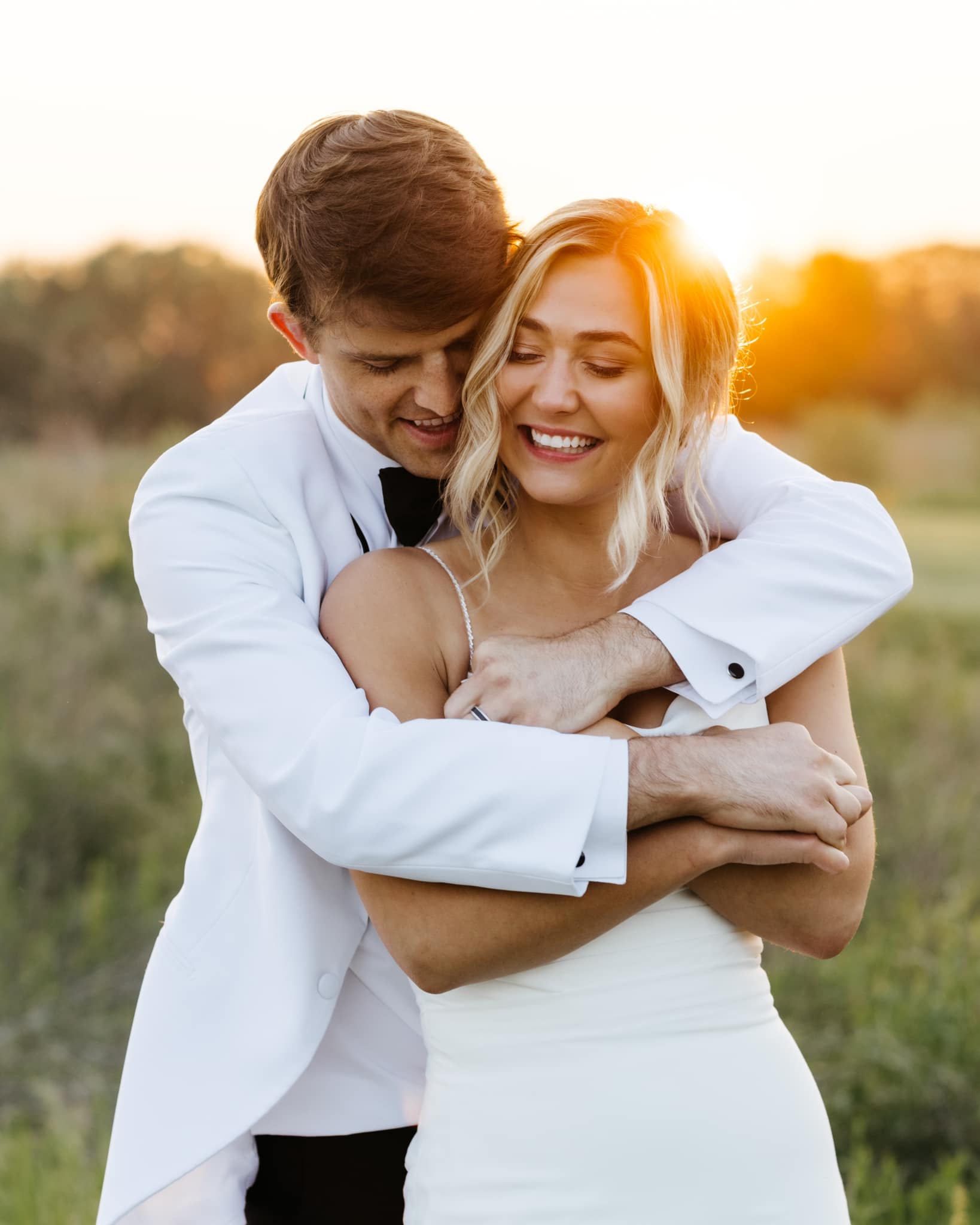groom hugging bride at sunset