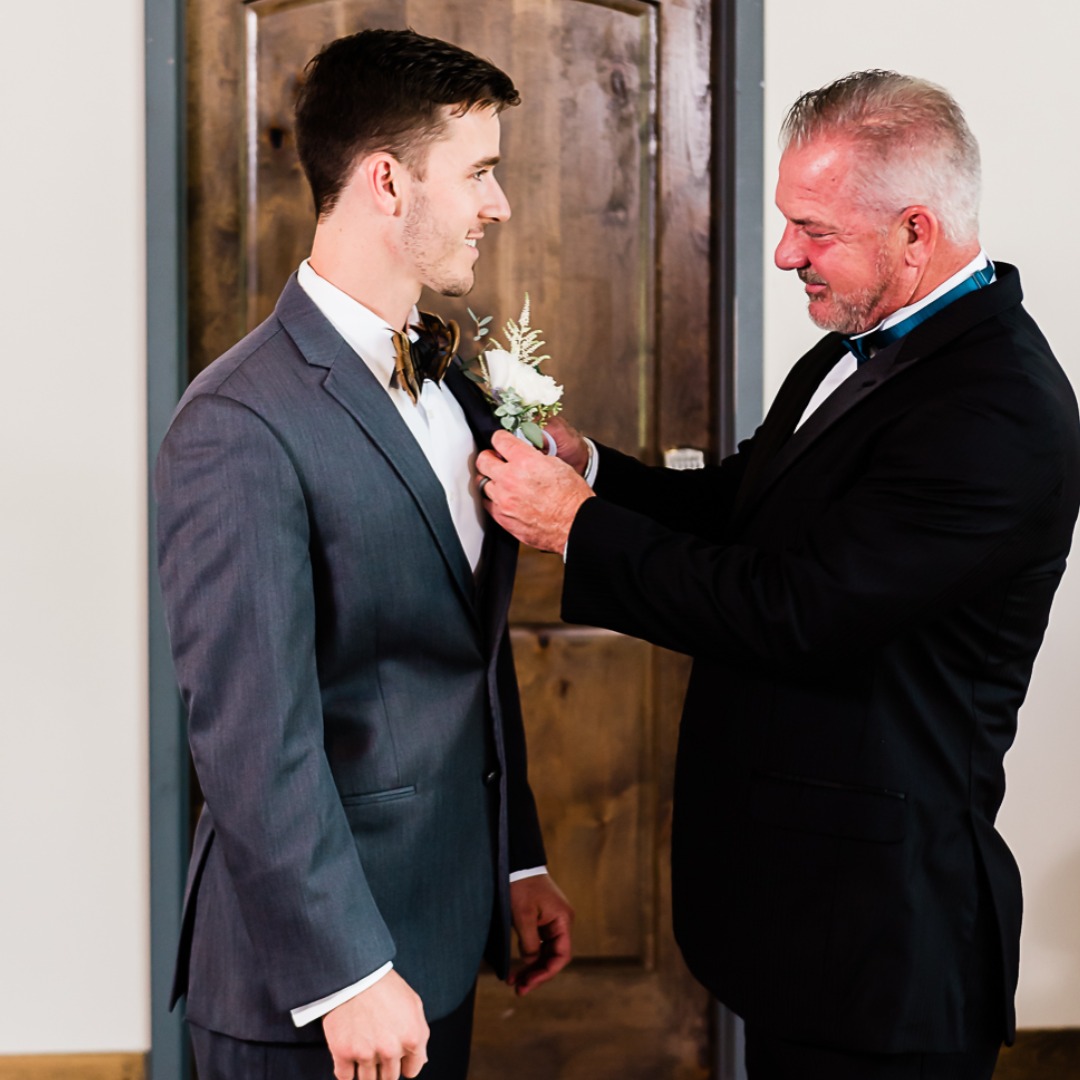 father of the groom pinning on groom's boutonniere