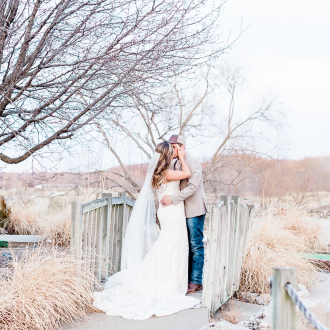 bride and groom kissing on wooden bridge