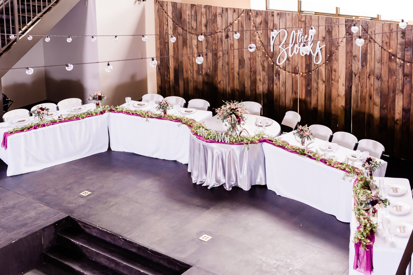 wedding party table in front of wooden backdrop with purple and green flowers