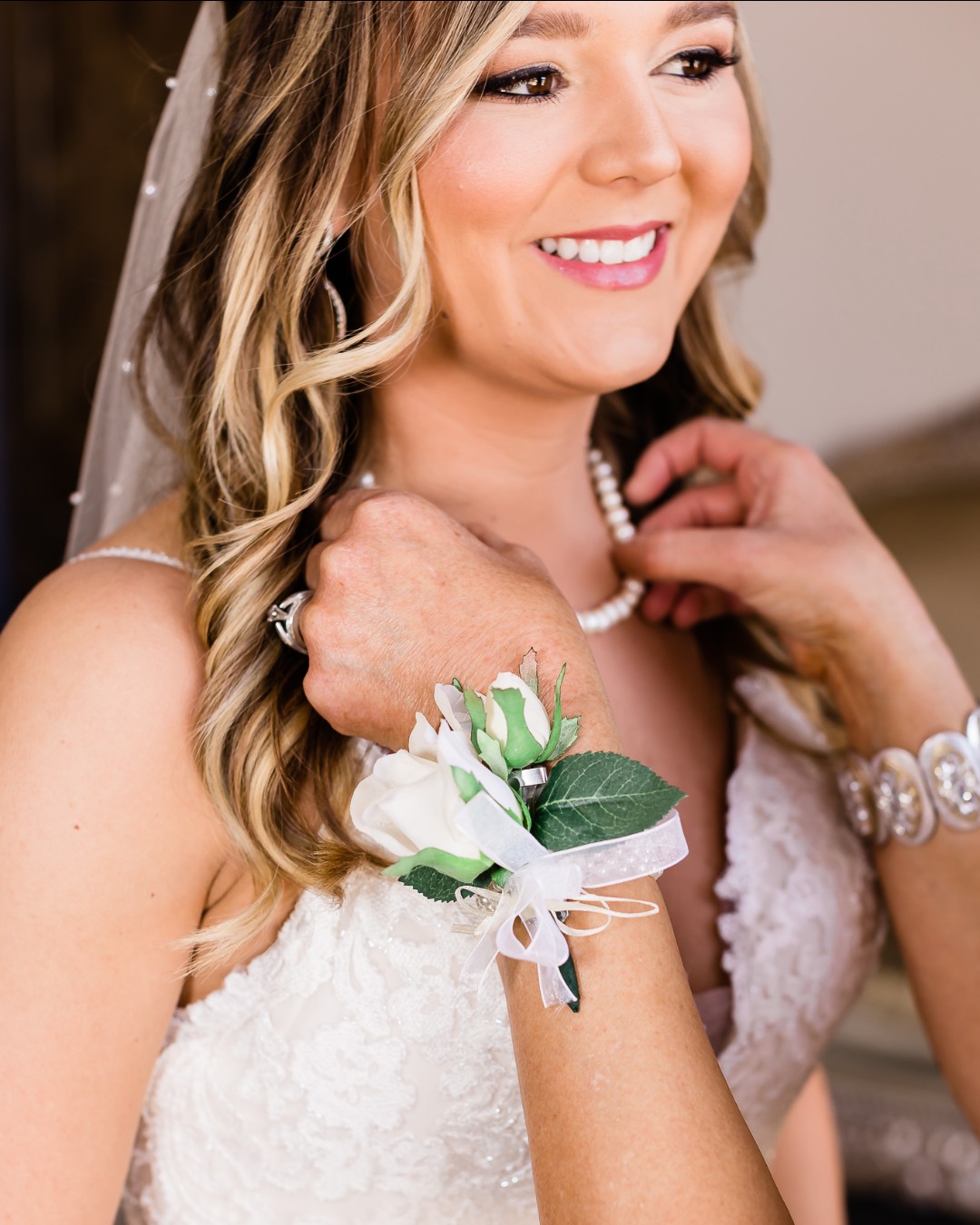 mother of the bride putting pearl necklace on bride