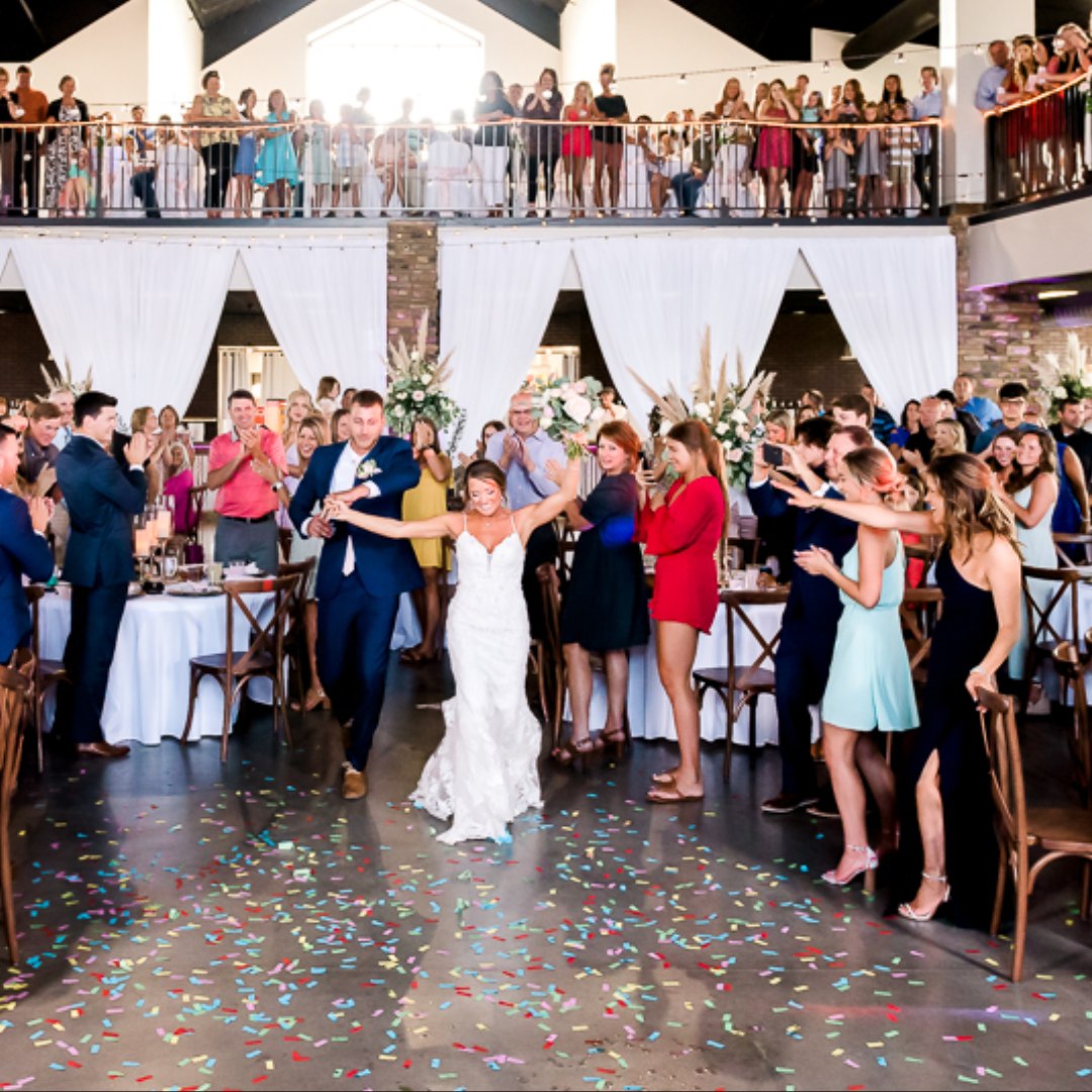bride and groom entering wedding reception while guests cheer