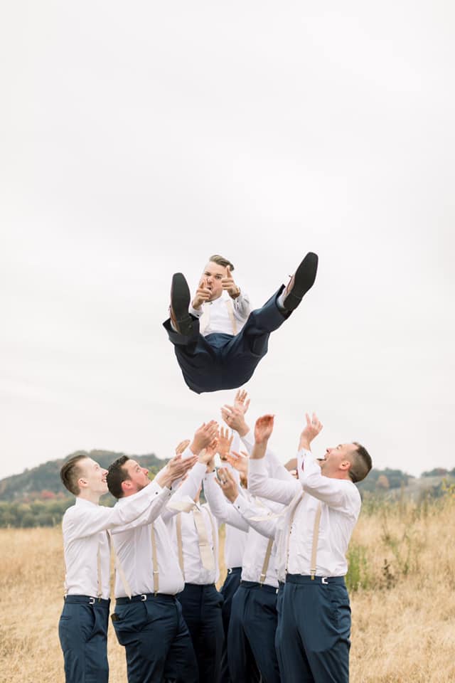 groomsmen throwing groom in the air